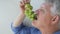 Older man eats green grapes