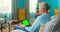 Older man at Home Sitting on a Couch Works on a Tablet with Green Mock-up