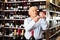 Older man inspecting quality of red wine in wine store in search of perfect wine for solemn occasion