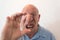 Older man looking through a large lens over nose and mouth, distortion, bald, alopecia, chemotherapy, cancer