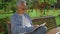 An older man sitting on the bench and reading book in park