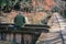 An older man sitting on a stone bridge across a water canal painting picture in the Philosophers walk in Kyoto, Japan. Autumn