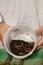 Older man working on his green bio garden showing earthworms in hands