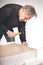 Older man working at home on kit of cabinet with laminated wooden drawers