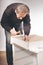 Older man working at home on kit of cabinet with laminated wooden drawers