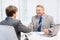 Older man and young man shaking hands in office