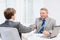 Older man and young man shaking hands in office