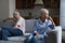 Older married couple sit on sofa feeling upset after quarrel