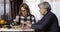 Older mother and daughter eat at the table in the room.