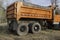 Older orange gravel or dump truck from back corner view