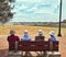 Older people facing the sea sit on bench