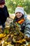 The older sister gathers a pile of leaves, and her younger brother helps her