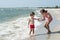 Older sister gives hand to younger little brother on the seashore