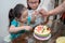 Older sister looking at the birthday cake being cut by the birthday girl. Celebration at home during quaratine