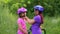 The older sister puts on the younger one a protective bicycle helmet in the park in the summer . Learning to ride a bicycle. Happy