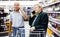 Older spouses talking on the phone in supermarket