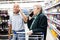 older spouses talking on the phone in supermarket