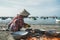 older vietnamese women with traditional hats clean scallops. fishing boats on sea near fishing village close to city Mui Ne, South