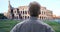 Older white gentleman looks around while sightseeing near Colosseum in Rome