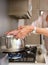 Older woman boiling water in pot on stove top