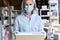 Older woman entrepreneur wearing face mask holding parcel box, portrait.