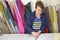 Older woman in a furniture factory is measuring and marking a grey material for the sofa with a chock