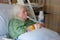 Older woman in hospital bed using incentive spirometer