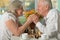 Older woman playing chess with her smart elderly husband at home