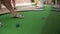 Older woman plays minigolf, detail only on her feet in gray sandals moving over green surface and blue ball moving to hole