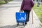 Older woman pushing wheeled basket on way to market