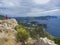 Older woman in red jacket looking at View of the Paleokastritsa bay and Monastery from the view point in the mediavel castle