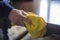 Older woman\'s hand dusting a polished wooden table, with a yellow duster.