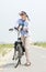 Older woman standing with bicycle on path on summer day