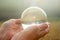 Older womans hand holding a shiny glass sphere