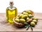 Olive berries and bottle of olive oil on the wooden table.