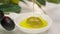 Olive oil is being poured from olive tree branch.