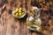 Olive oil in a bottle and fruits of olives in a bowl. Olive oil bottle and olives on wooden background with copy space