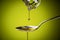 Olive oil flowing  on spoon on green background