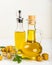 Olive oil in glass bowls, gravy boats and bottle on a textured kitchen table.