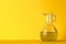 Olive oil in glass jar on yellow background