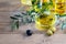 Olive oil in glass transparent bowl and assortment of olive oil bottles on the natural wooden background