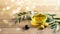 Olive oil in the glass transparent bowl, branches of the olive tree and some olives on the wooden natural background