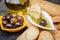 Olive oil sauce in white bowl & Greek olives on wood background
