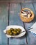 Olives in a flat sink and a wicker basket with sea shells, marine-themed paper napkins