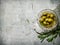 Olives with rosemary on a stone stand.