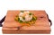 Olivier salad with shrimp, pickled cucumber, egg, decor of boiled carrots and peas on a wooden tray, board, dish. The object is