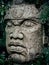 Olmec sculpture carved from stone. Big stone head statue in a jungle