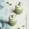 Ombre layered green smoothies with mint in jars, square crop