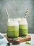 Ombre layered green smoothies with straws in glass jars