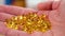 Omega 3 translucent golden capsules. Handful of dietary nutritional supplements in hand.